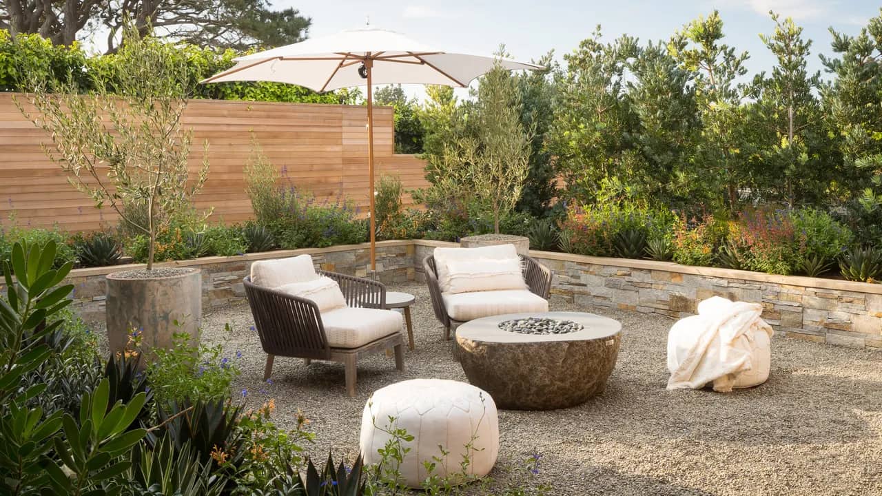 Modern fire pit with gravel surrounded by low walls. Custom landscaping. Credit to Architectural Digest.