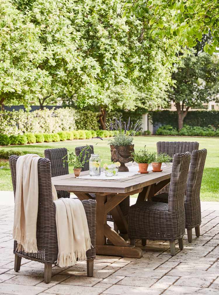 Weathered interlock paving stones with rustic table and chairs. Credit to Better Homes & Gardens.