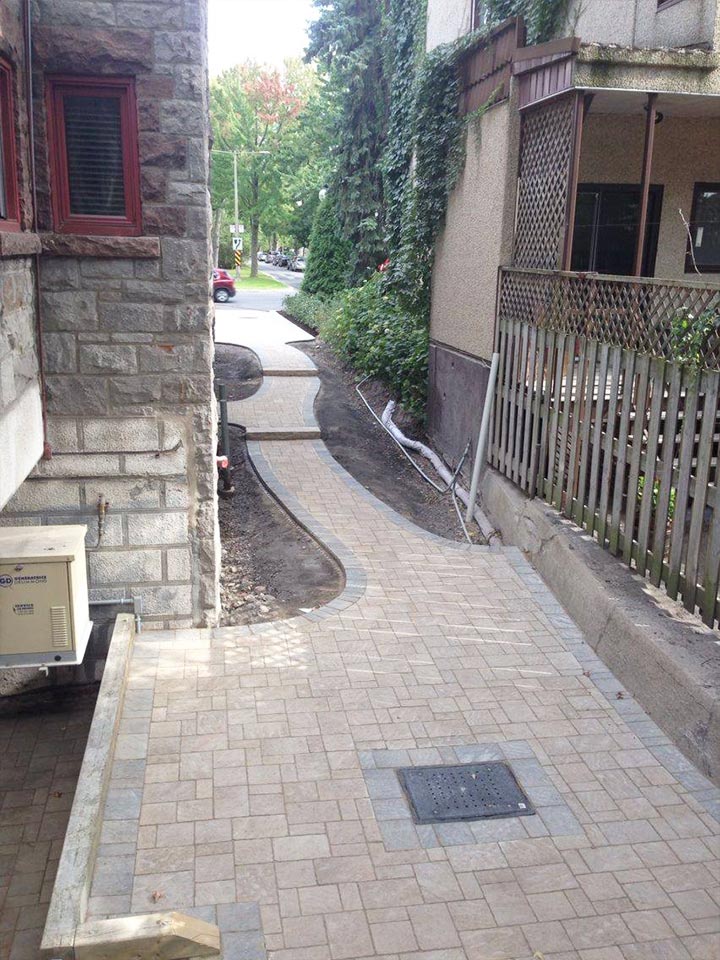 Home side entrance that is built out of paving stone in Montreal by Large stone paved driveway in front of a luxury home in Montreal done by L'Entreprise Générale Paysagiste Riccardi