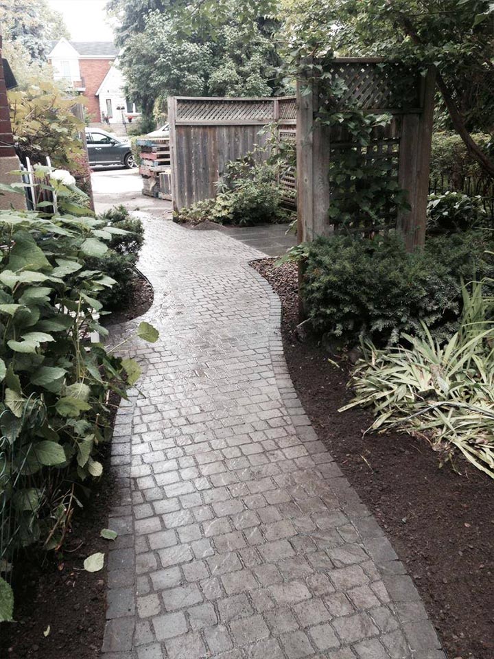 Paving stone side entrance of home by Large stone paved driveway in front of a luxury home in Montreal done by L'Entreprise Générale Paysagiste Riccardi