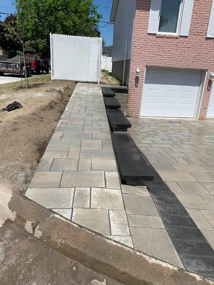 Side entrance of a home with wet stone slabs, Large stone paved driveway in front of a luxury home in Montreal done by L'Entreprise Générale Paysagiste Riccardi